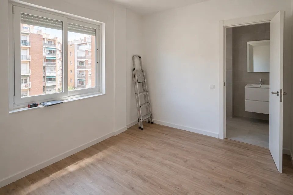 Salón de un piso recién reformado con un medidor láser y una carpeta cerrada sobre la repisa de la ventana