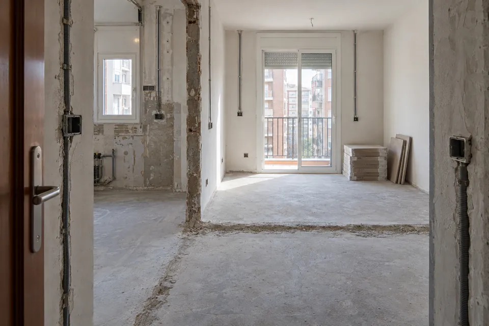 Piso pequeño en obras con el tabique de la cocina recién derribado y tubos eléctricos nuevos